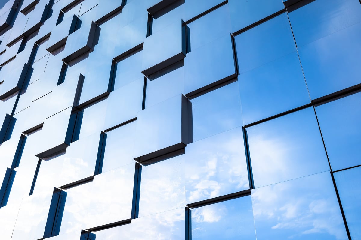 Contemporary glass facade of a commercial building featuring repeating geometric windows and reflective minimalist architecture